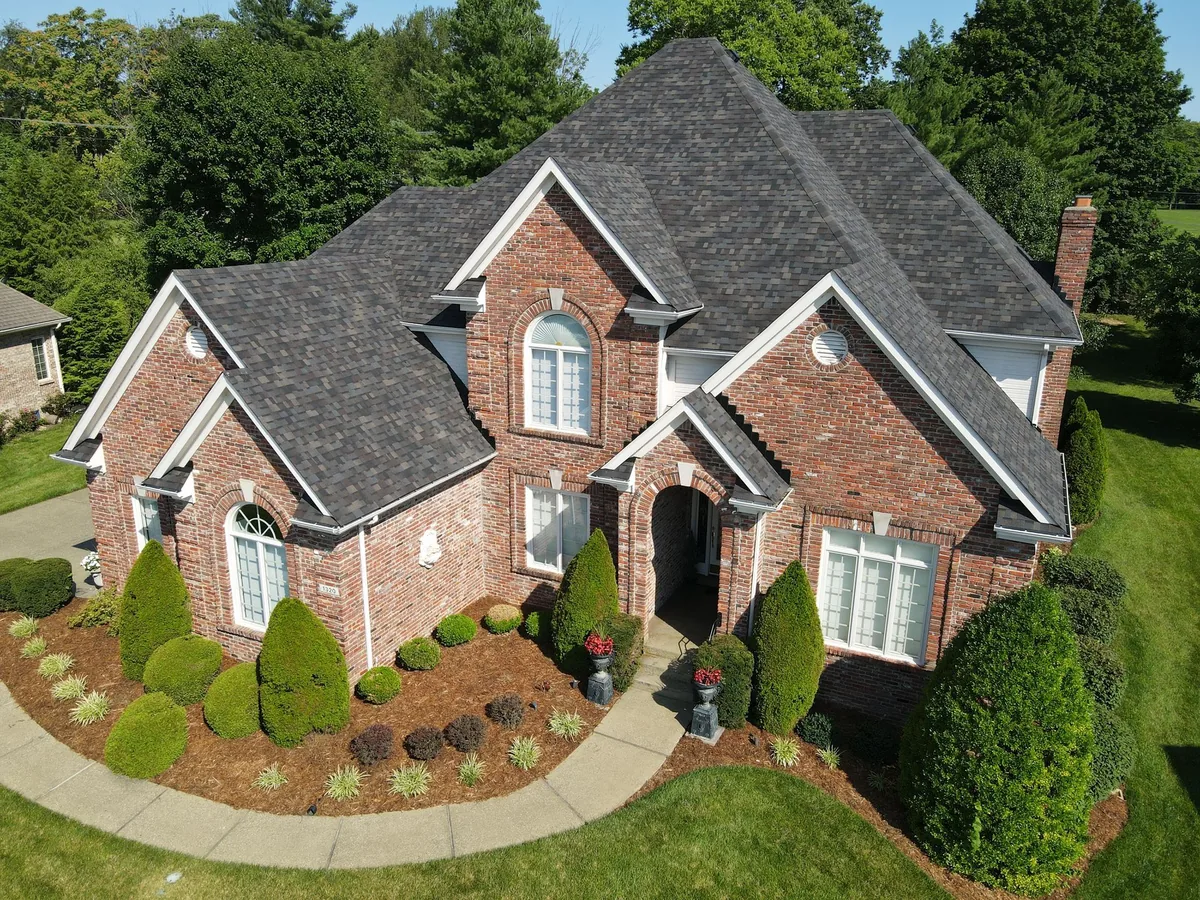 Aerial view of a brick home in Louisville, KY with a new dark shingle roof installed by Integrity Roofing and Construction