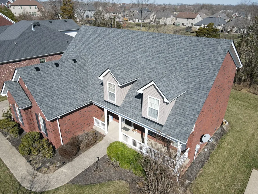 Aerial view of a brick house with a new gray shingle roof